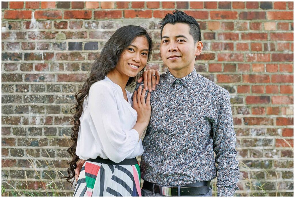 Wedding couple smiling in front of a brick wall