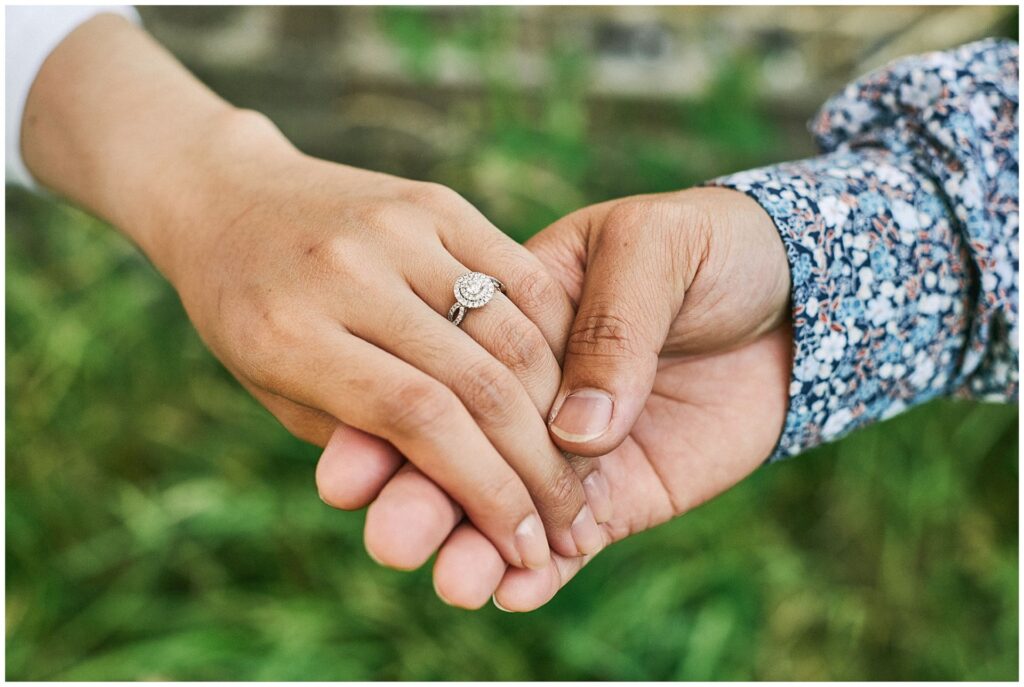 Engaged couple holding hands with diamond engagement ring on.