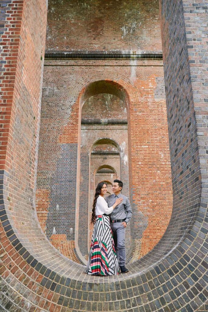 Happy couple laughing together whilst stood under The Ouse Valley Viaduct surrounded by brick