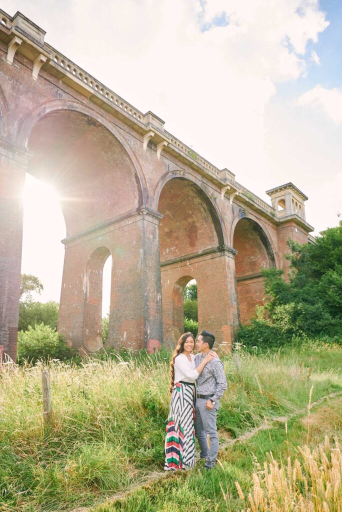 Engaged couple smiling at sunset in front of The Ouse Valley Viaduct