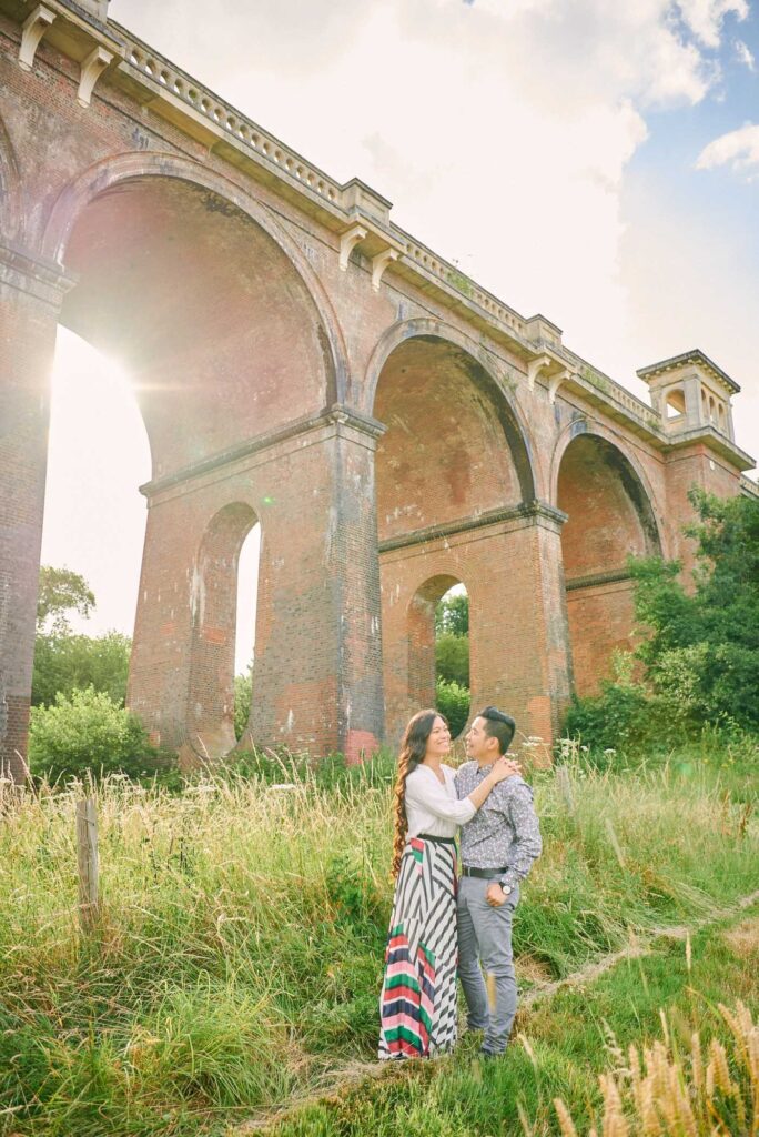 Engaged couple hugging at sunset in front of The Ouse Valley Viaduct