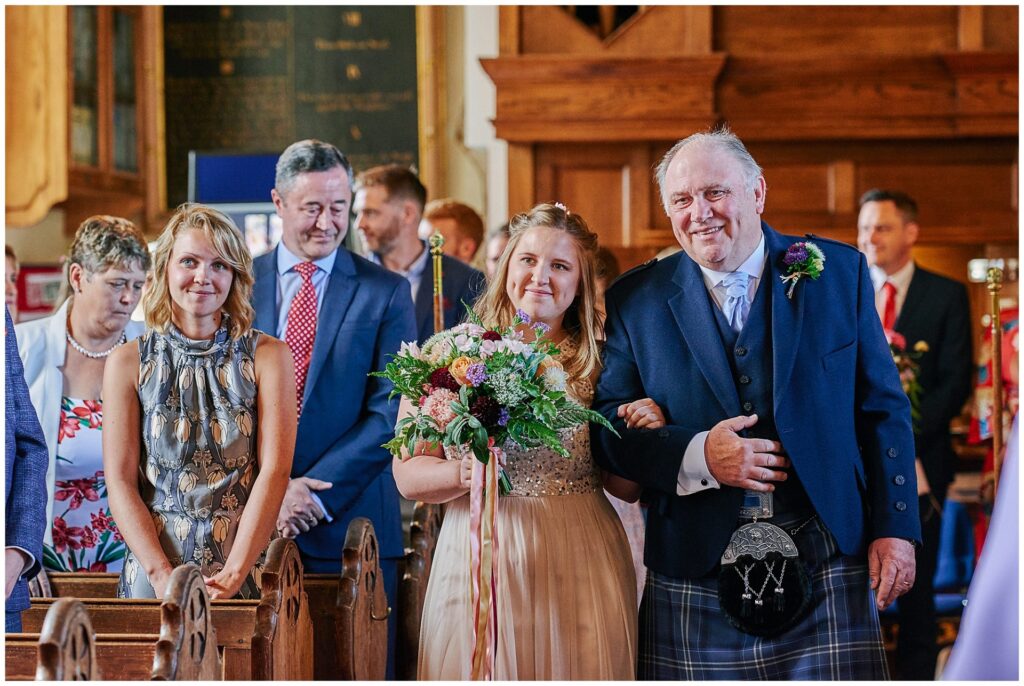 happy bride walking with her dad down the isle in Essex