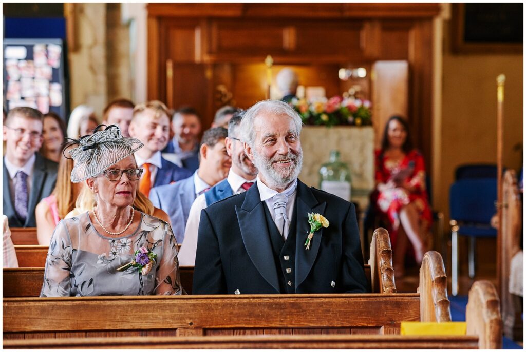 smiling wedding guest sat in a church in Essex