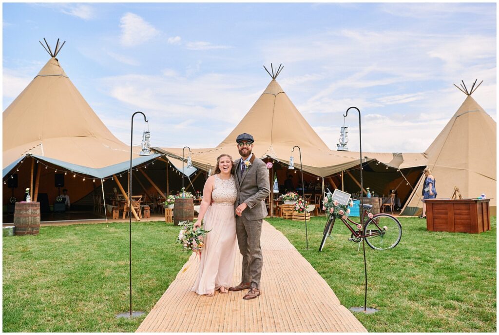 Bride and Groom on their wedding day laughing in front of a tipi in Essex