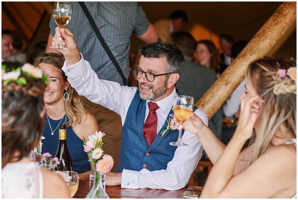 Guests toasting each other inside a festival tipi tent in Essex