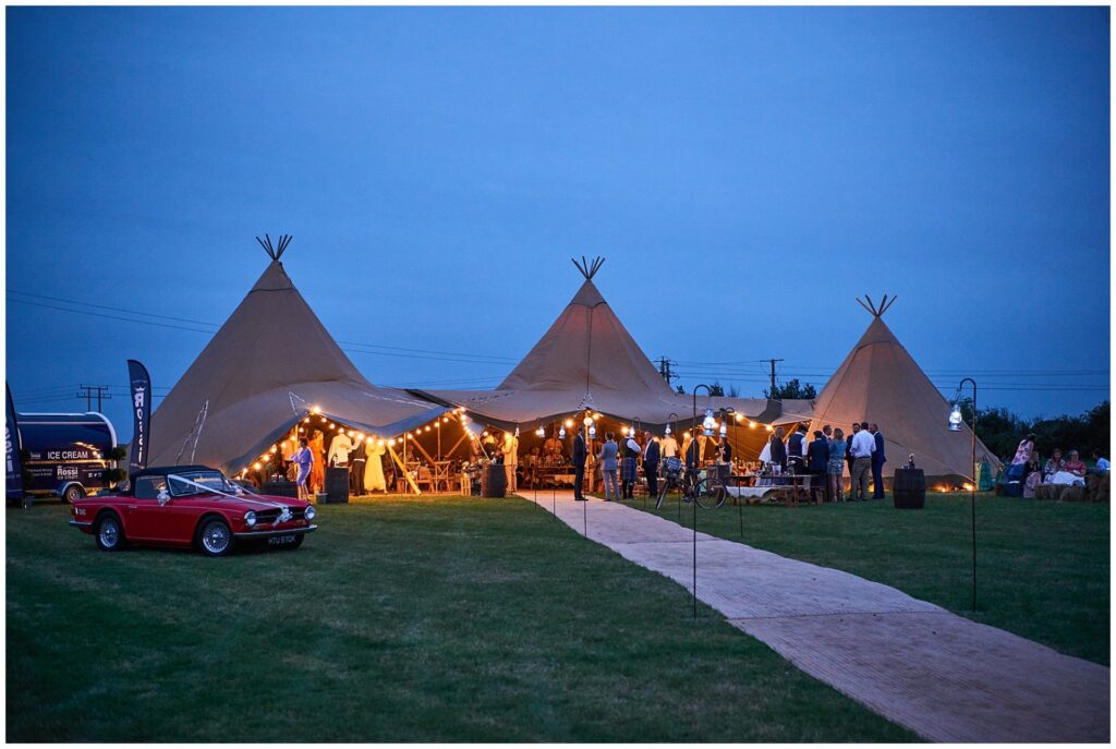 Festival tipi lit up at night with outdoor bulbs during summer wedding in Essex