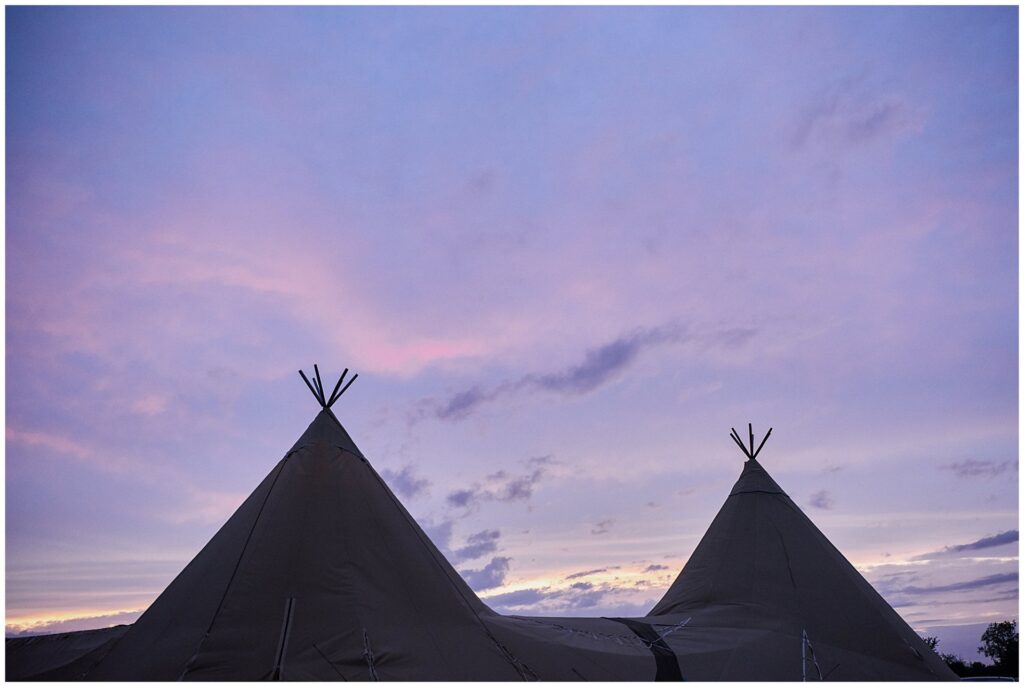 silhouette of a festival tipi at night with purple sky behind