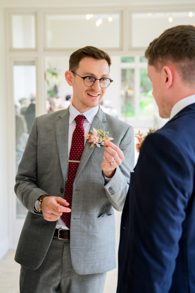 groom preparing boutonniere before ceremony at woodborough hall wedding