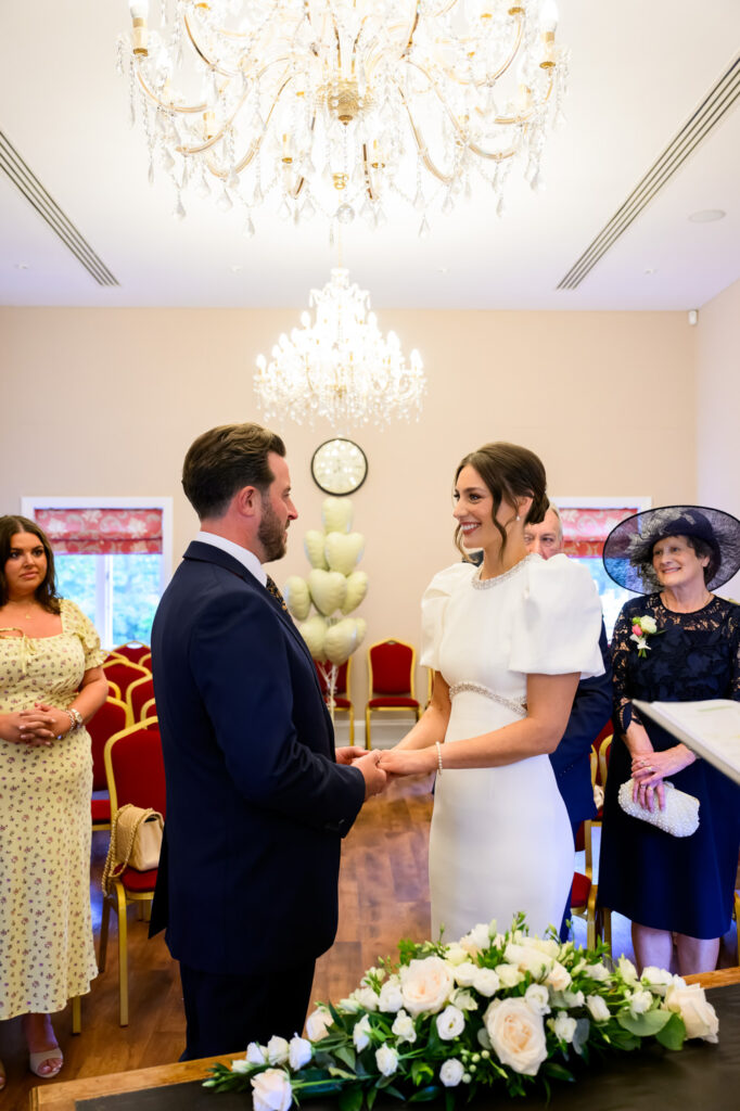 Bride and groom holding hands during their ceremony at West Bridgford Registry Office