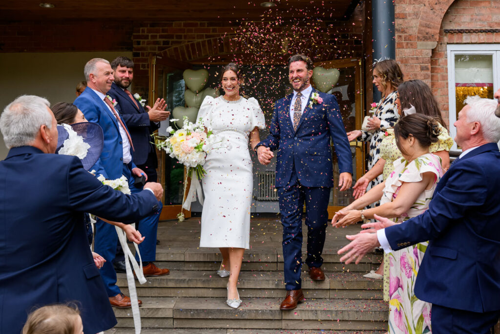 Bride and groom walking through confetti outside West Bridgford Registry Office in Nottingham