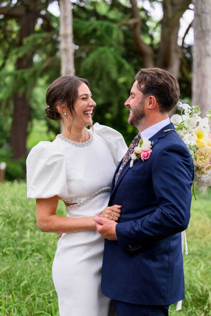 Bride and groom laughing together during wedding portraits in West Bridgford Park