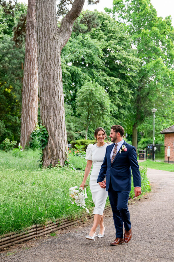 Bride and groom walking through West Bridgford Park after their registry office wedding