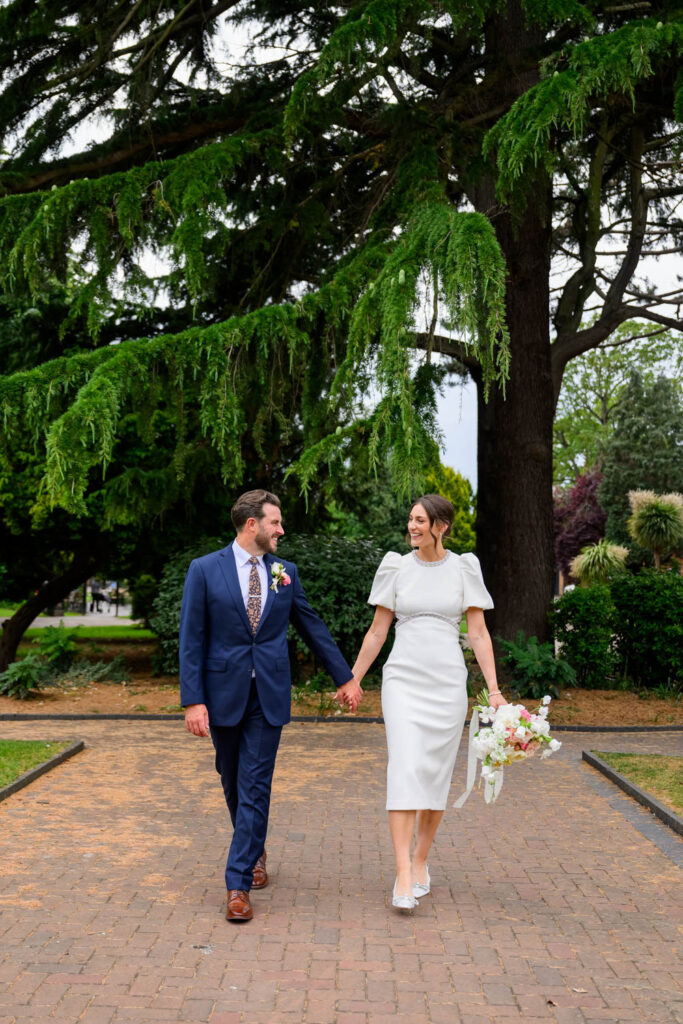 Bride and groom walking together in West Bridgford Park after their wedding ceremony
