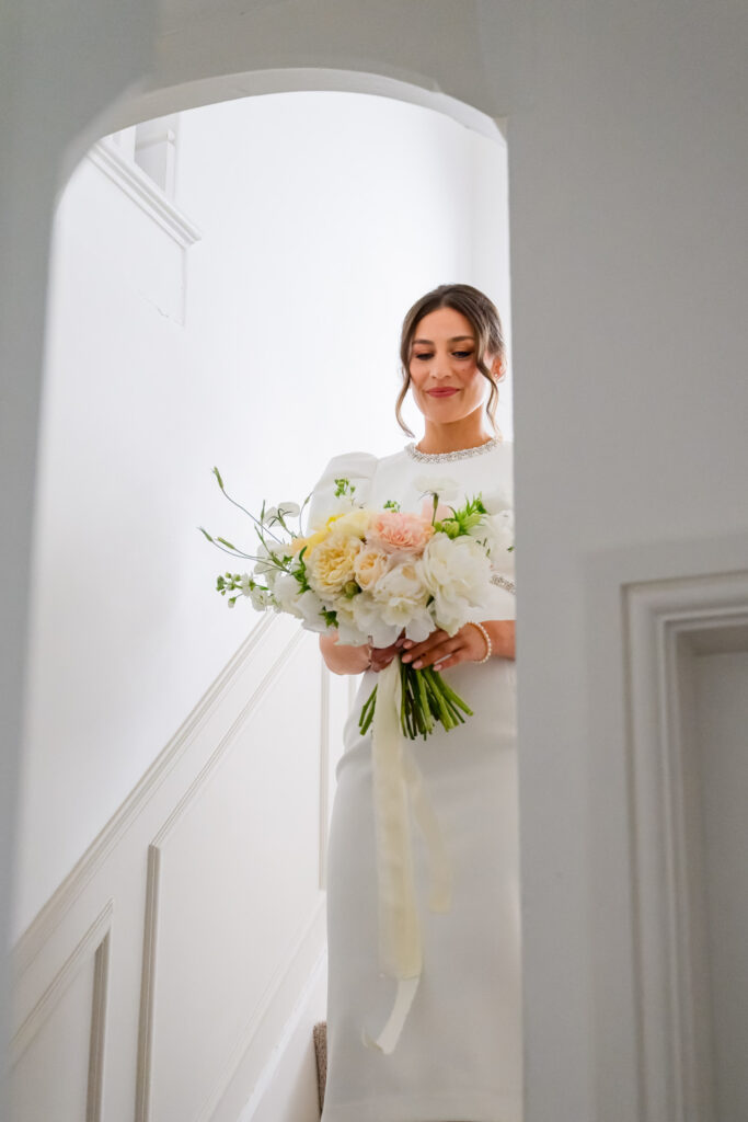 Bride walking downstairs with her bouquet before leaving for the ceremony