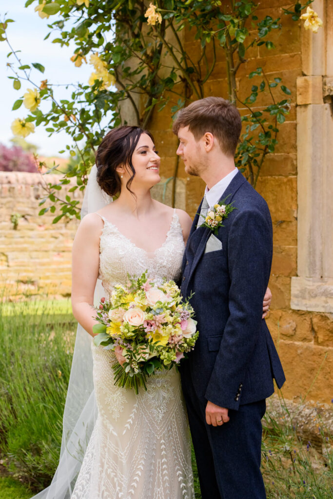 Bride and groom portrait beside the ivy-covered stone house