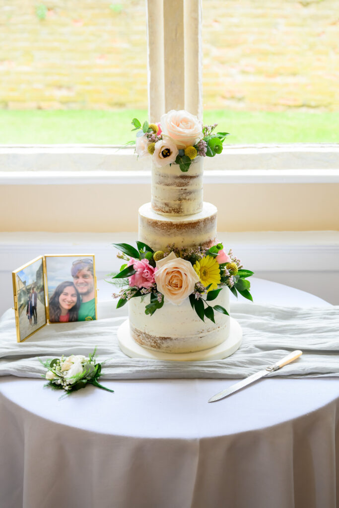 Three-tier rustic wedding cake decorated with fresh flowers