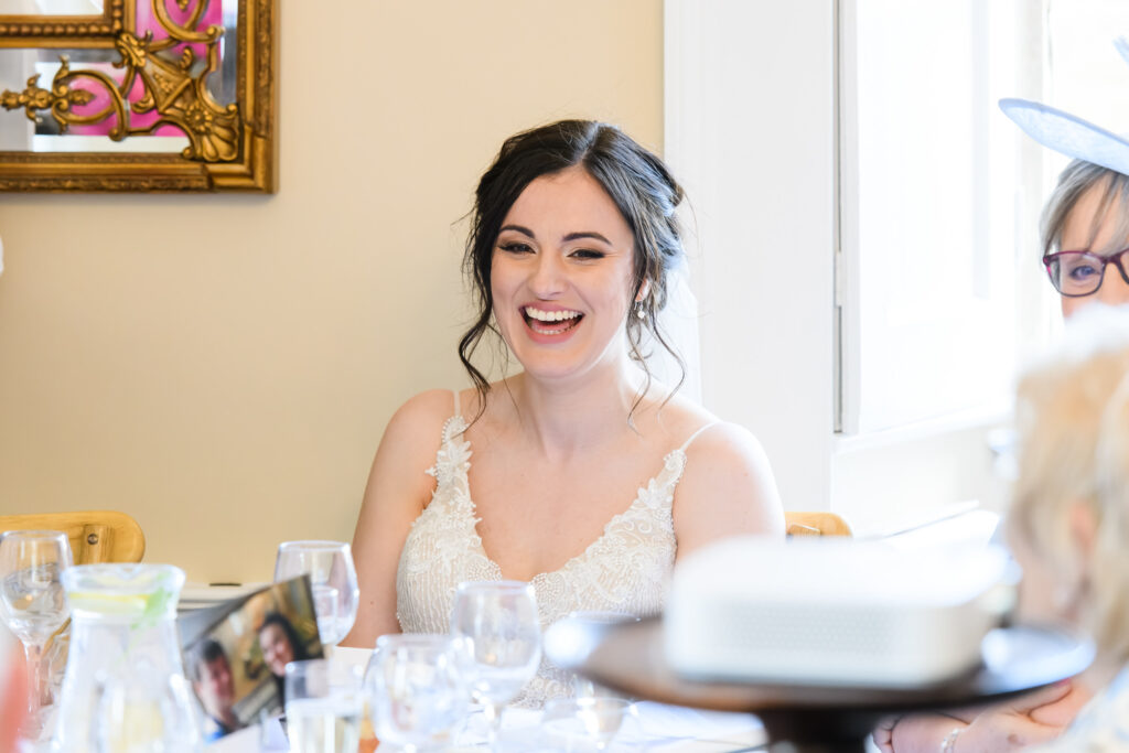 Bride laughing during speeches at the wedding breakfast