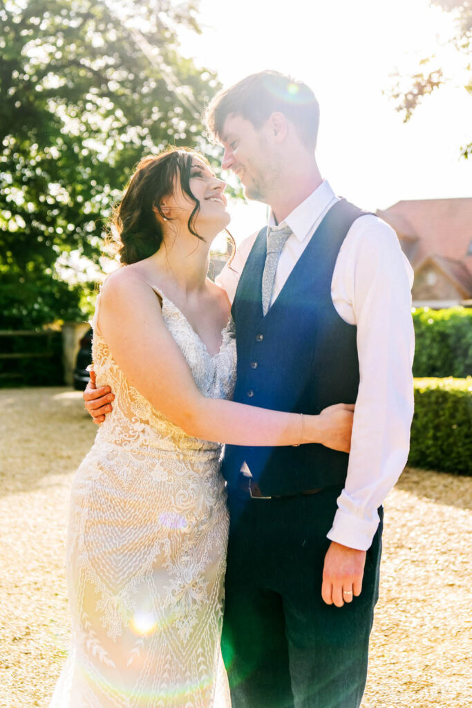 Bride and groom embracing in warm evening sunlight