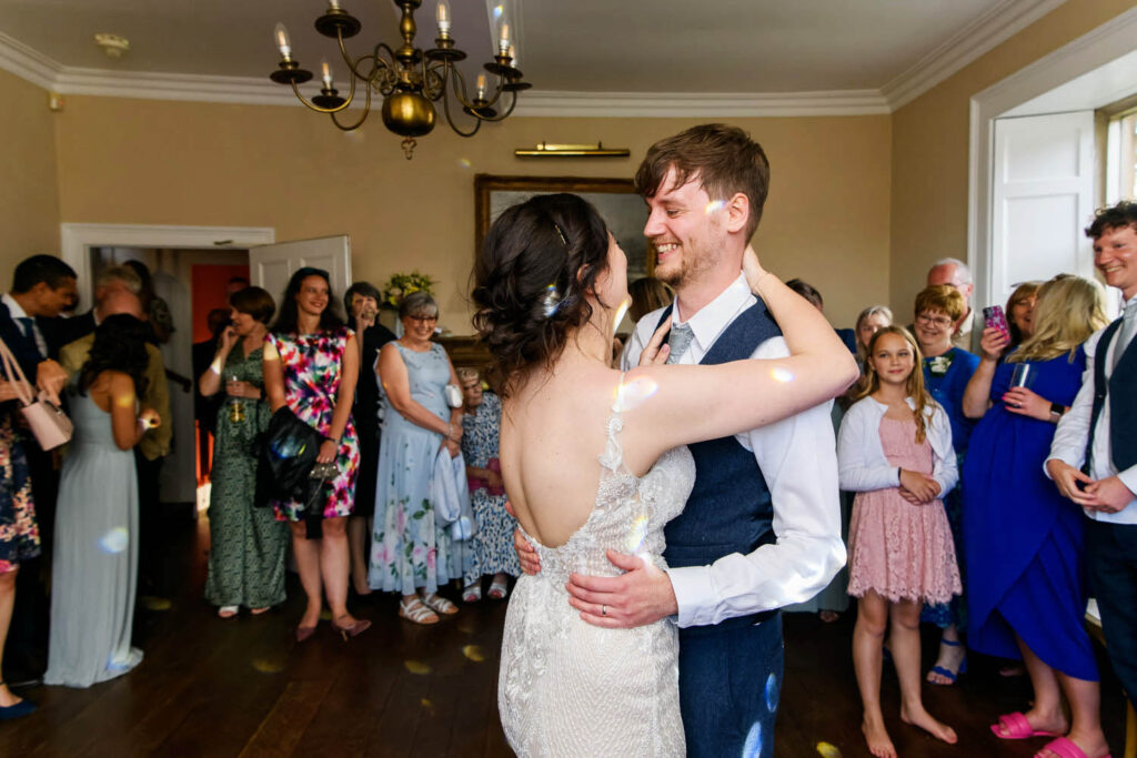 Bride and groom sharing their first dance surrounded by guests