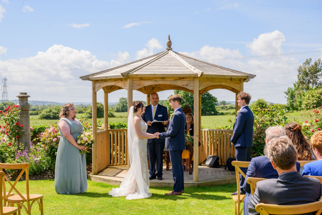 Outdoor wedding ceremony at Allington Manor in Lincolnshire with bride and groom exchanging vows beneath the garden gazebo