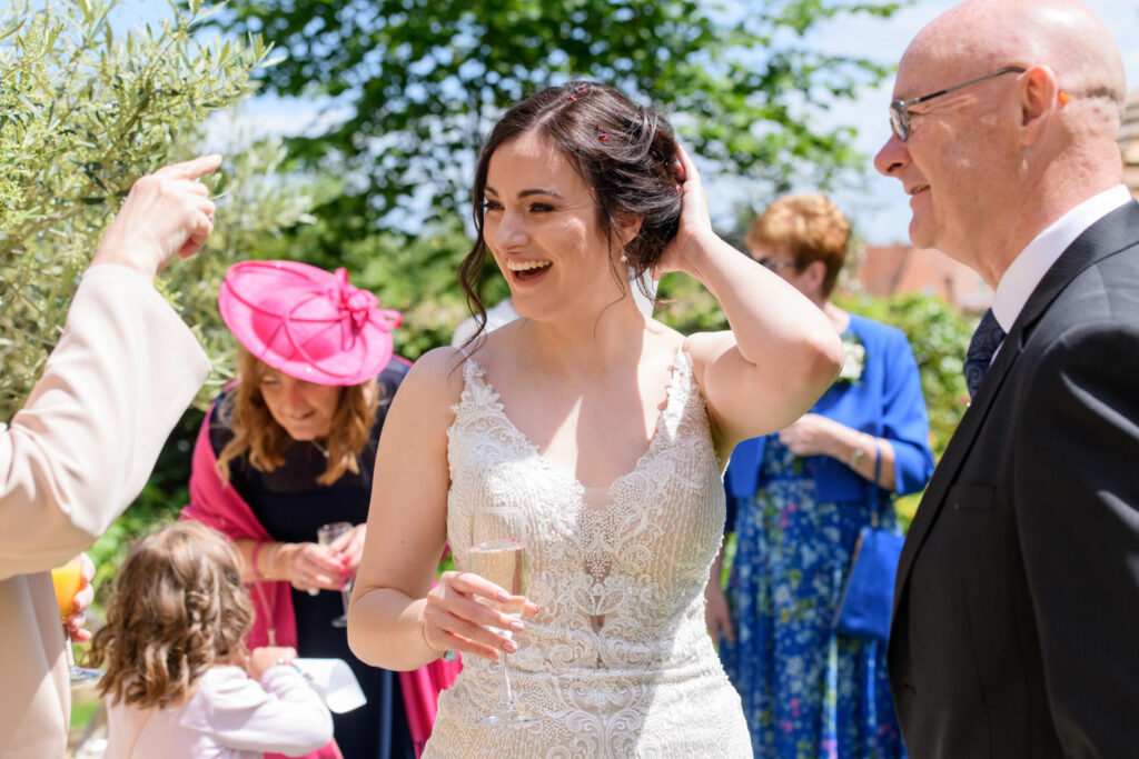 Bride greeting guests during sunny garden drinks reception at Allington Manor wedding