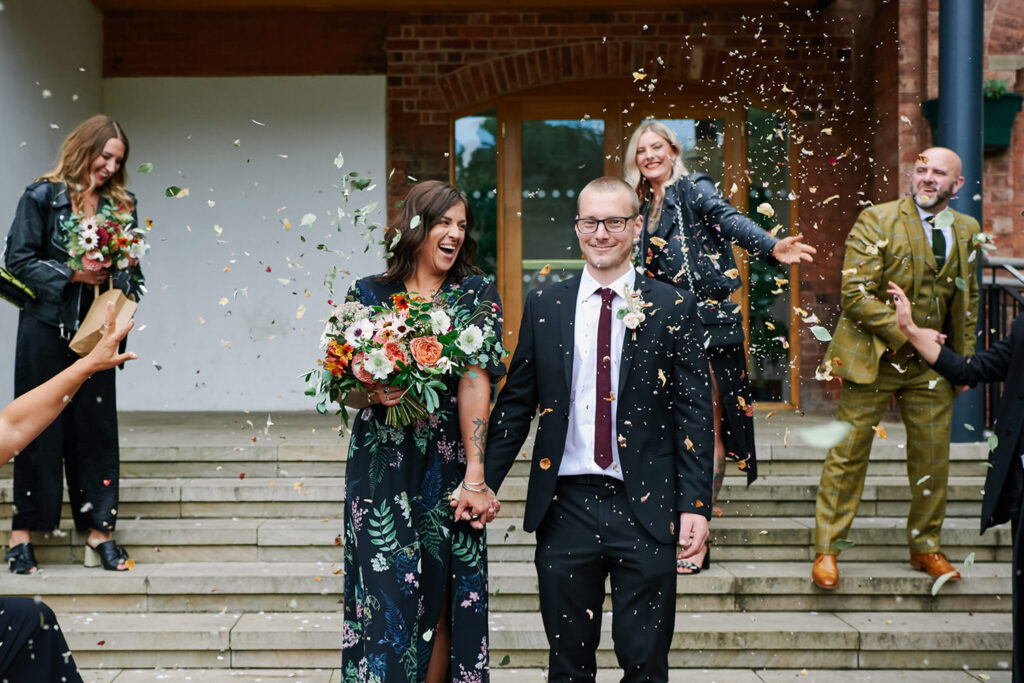 alternative couple walking through confetti outside registry office