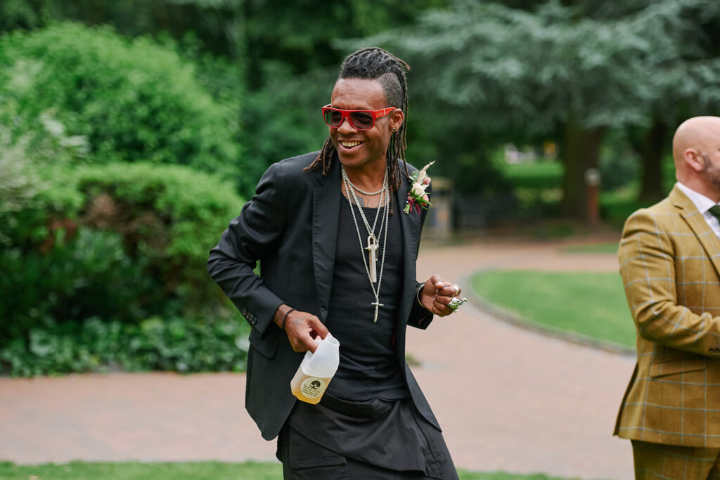 Wedding guest dancing with a drink during outdoor celebrations after a Nottingham wedding
