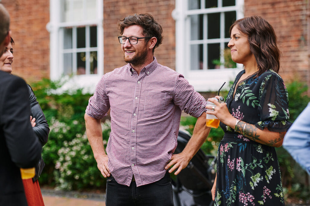 happy wedding guest in front of brick wall