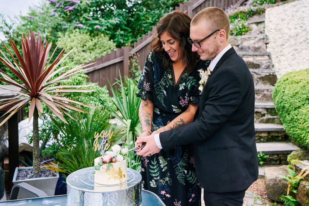 Bride and groom cutting their wedding cake during relaxed outdoor celebrations