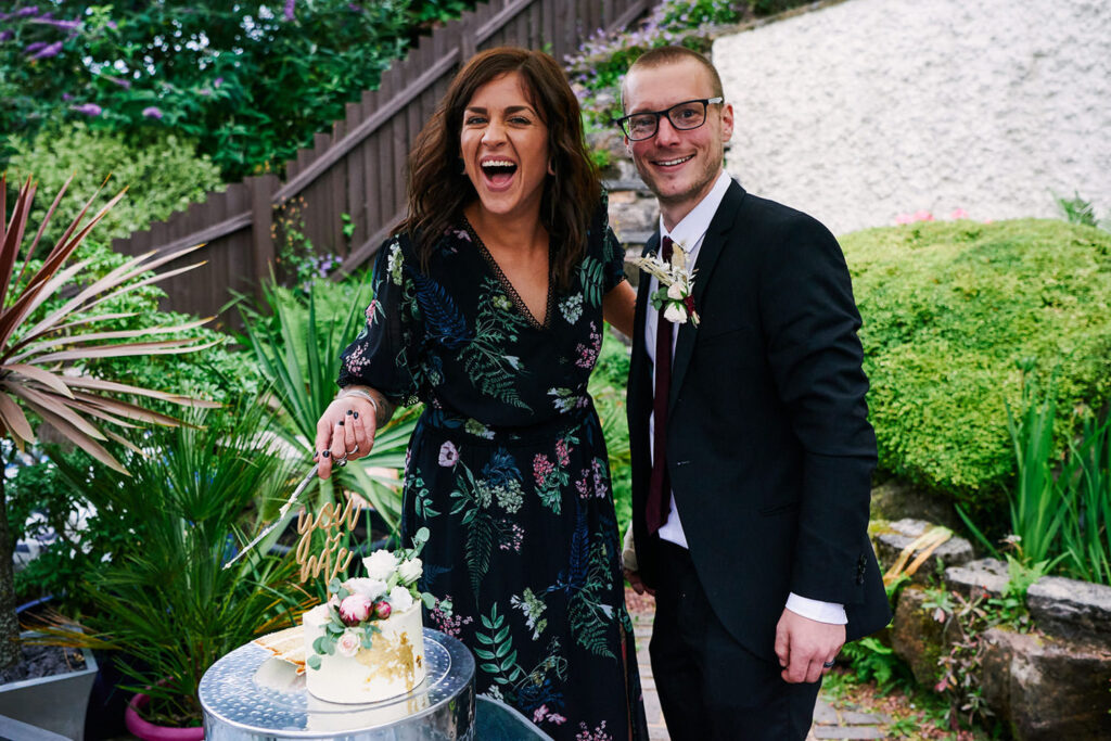 Tattoeed bride and groom laughing after cutting their wedding cake