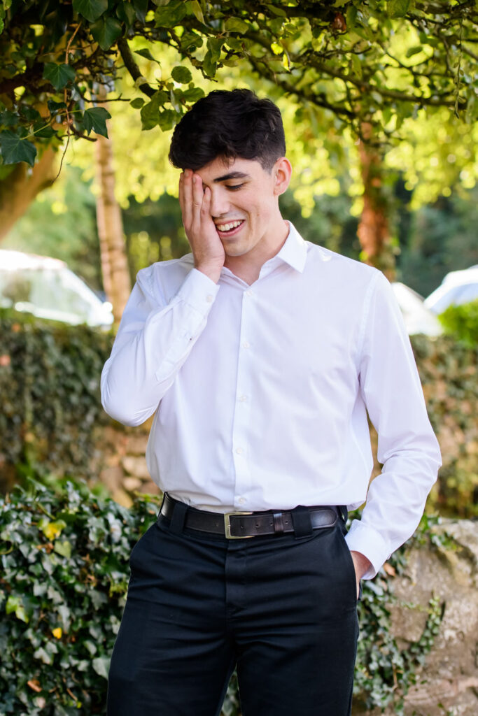 Groomsman reacting emotionally during drinks reception in shaded garden area at countryside wedding