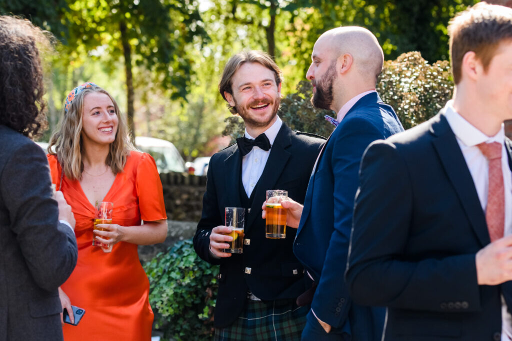 Guests laughing and chatting with drinks during relaxed countryside wedding reception at Knockerdown Cottages