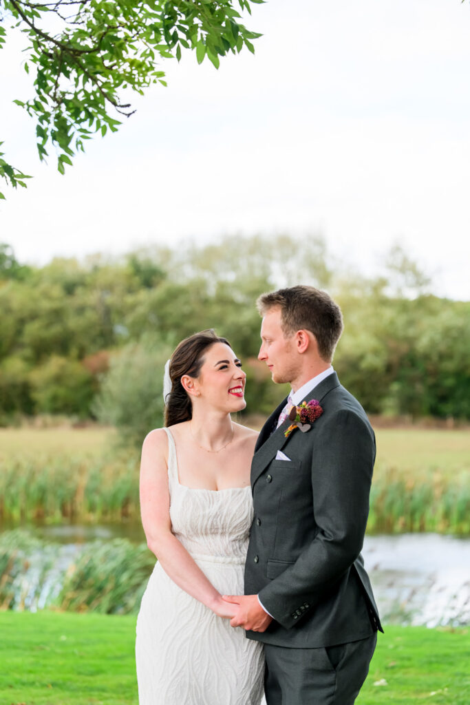 Bride and groom portrait beside lake at countryside wedding venue