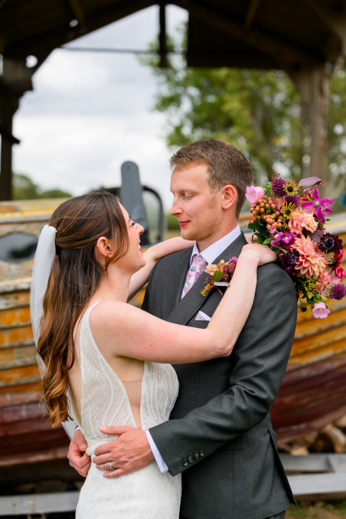 Bride and groom photography in front of rustic boat at Willow Marsh Farm