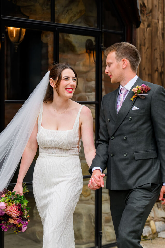 Bride and groom walking together outside rustic barn wedding venue