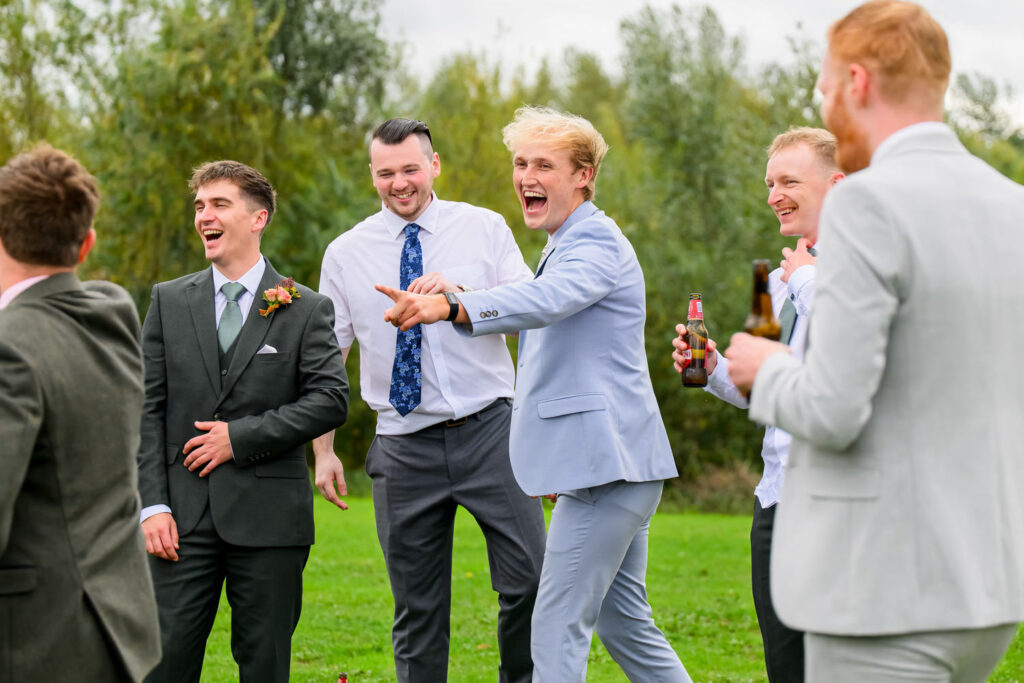 Groomsmen laughing together during relaxed outdoor wedding reception
