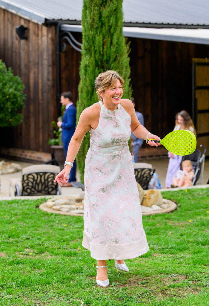 Wedding guest playing garden badminton during outdoor drinks reception