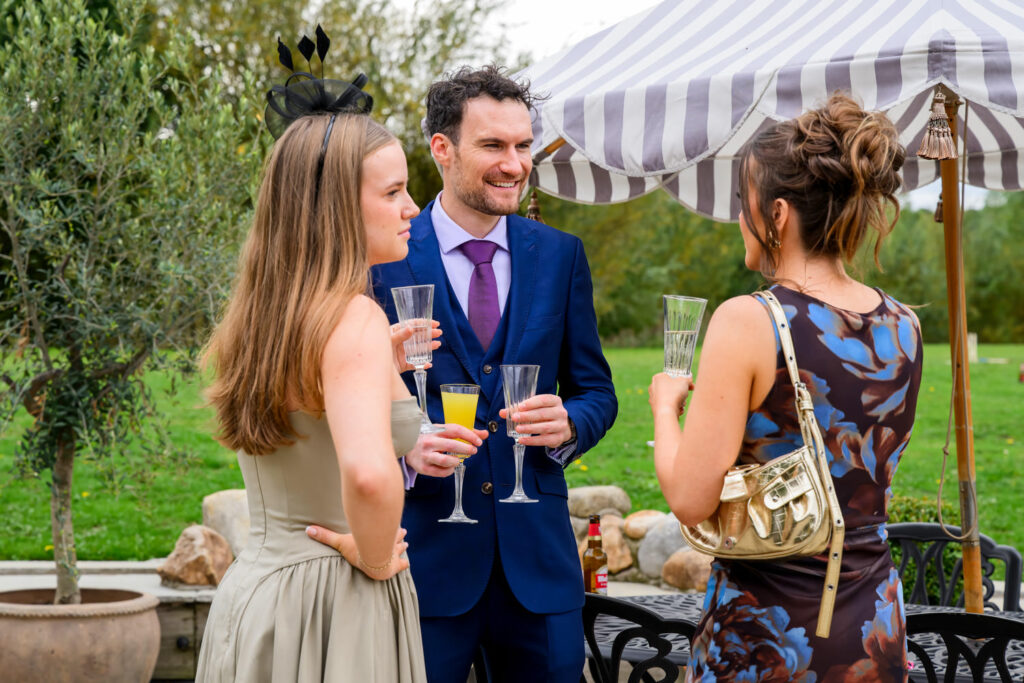 Wedding guests chatting with drinks during outdoor drinks reception
