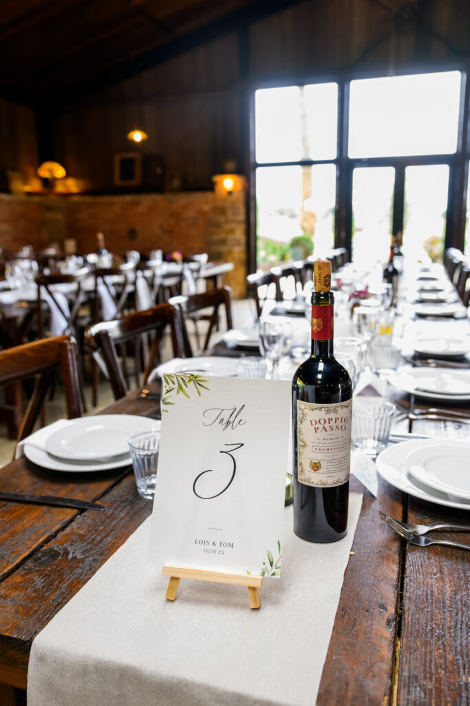 Rustic barn wedding table setup with wine and table number card