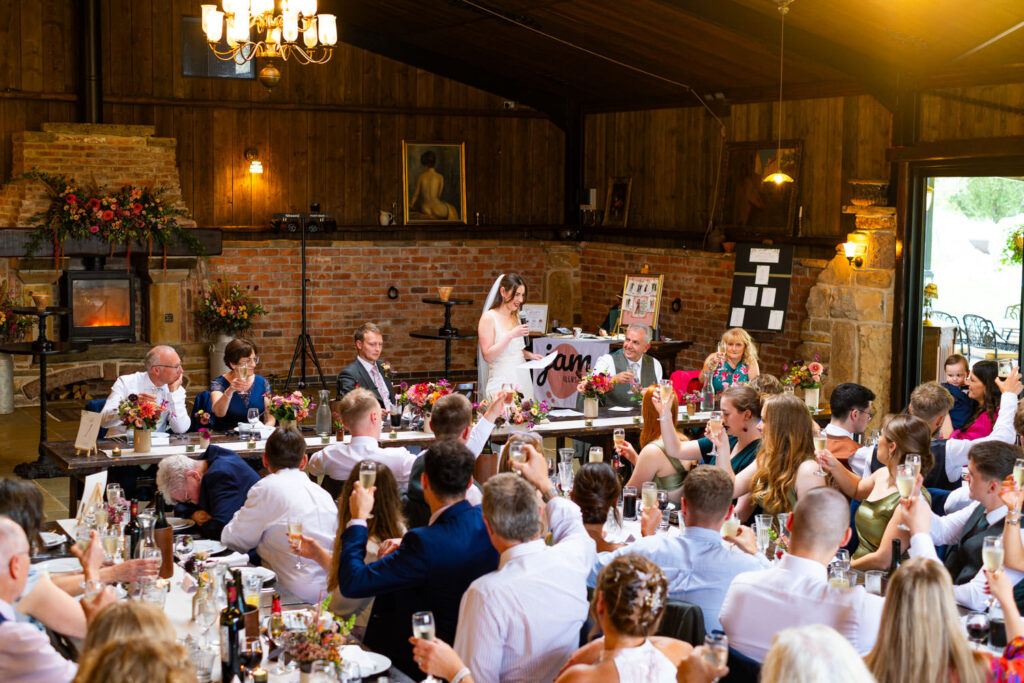Bride giving speech during rustic barn wedding reception
