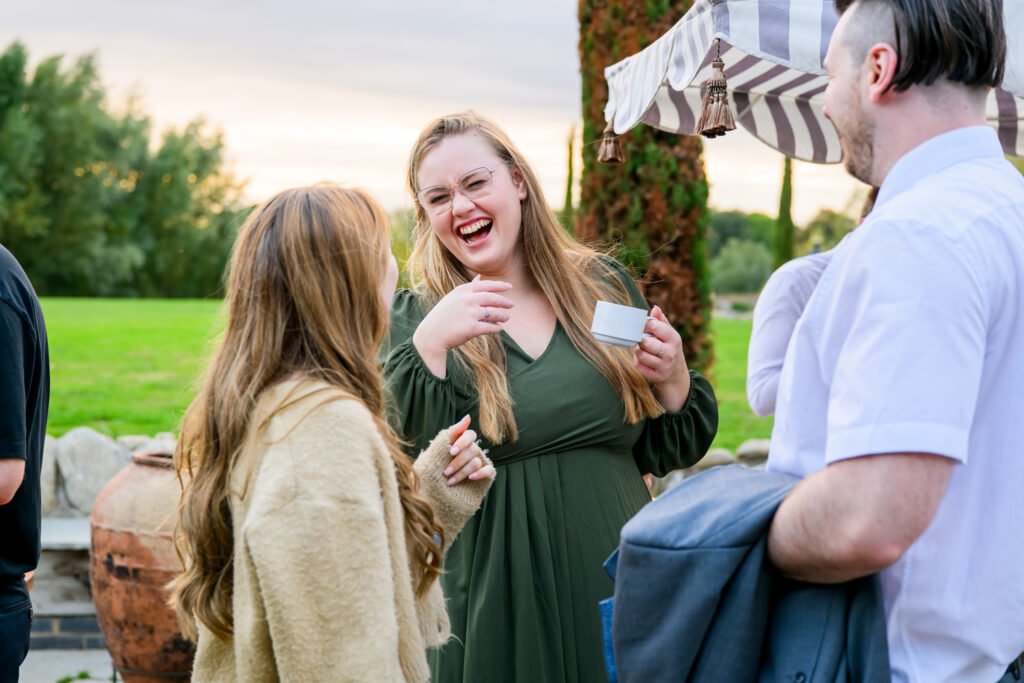Wedding guests laughing together during relaxed evening drinks reception