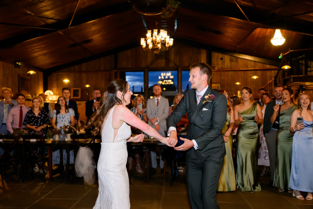 Bride and groom dancing together during their first dance surrounded by guests