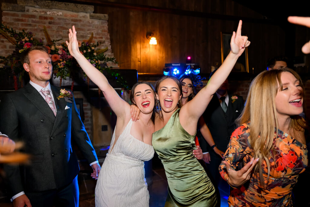 Bride celebrating with friends on packed dancefloor during wedding party
