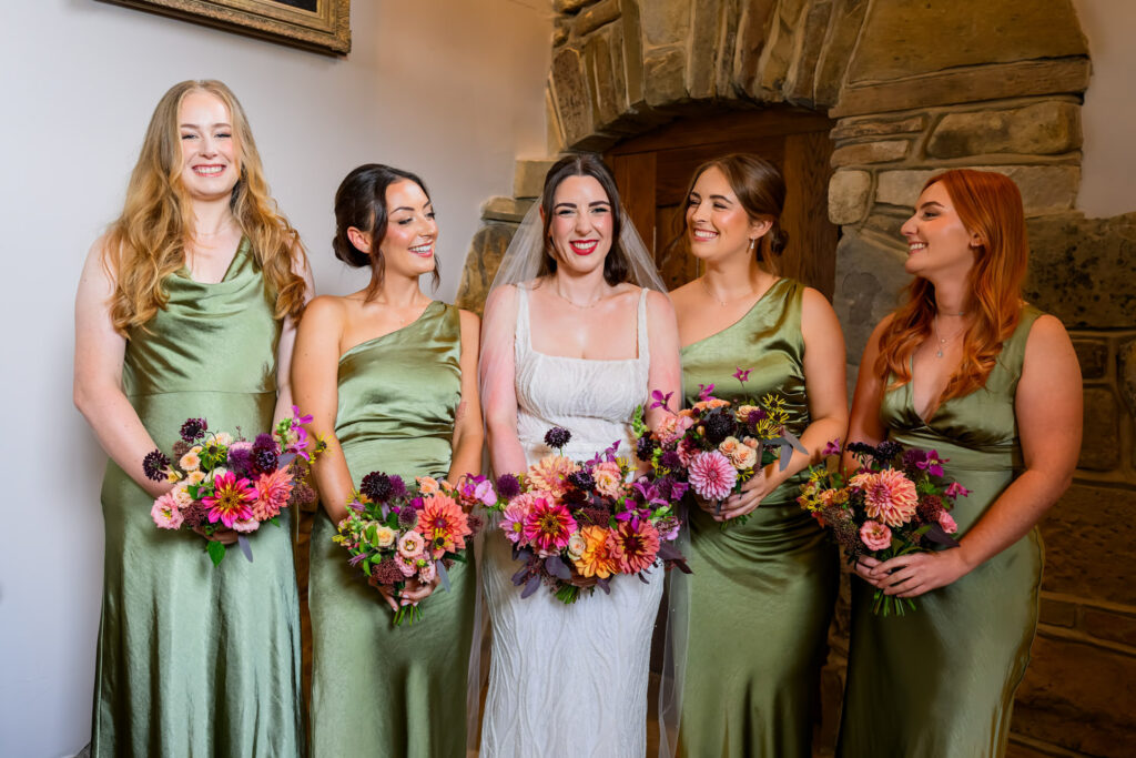 bridesmaids smiling with bride in front of stone wall in the bridal suite