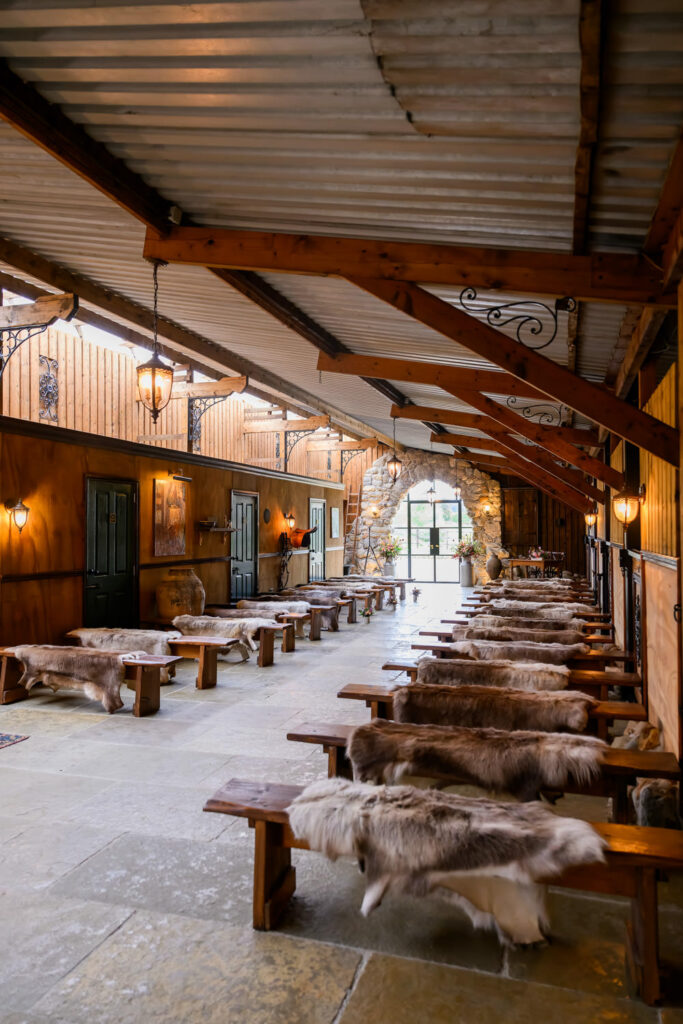 Rustic barn ceremony setup with wooden benches and sheepskin rugs at Willow Marsh Farm