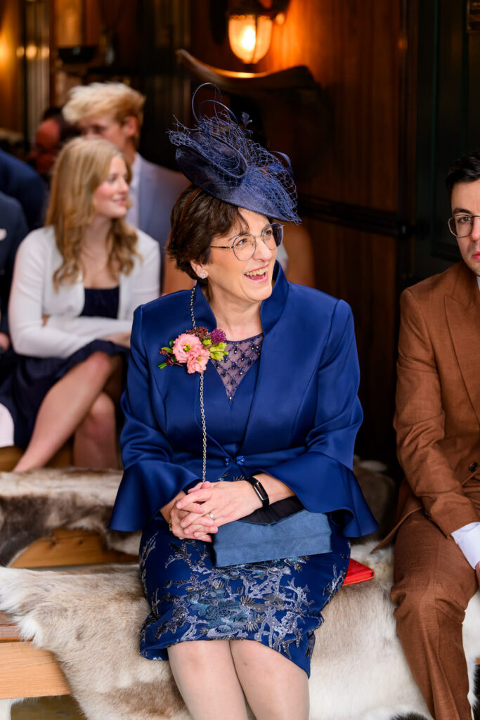 Wedding guest wearing navy fascinator smiling during barn ceremony