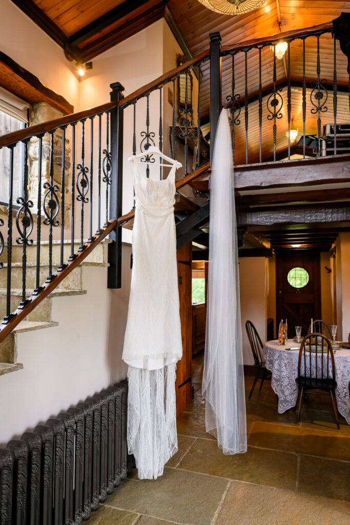 Bride’s wedding dress hanging on staircase during bridal preparations at Willow Marsh Farm wedding venue