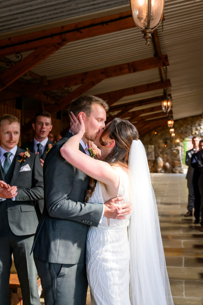 Bride and groom sharing their first kiss during the wedding ceremony