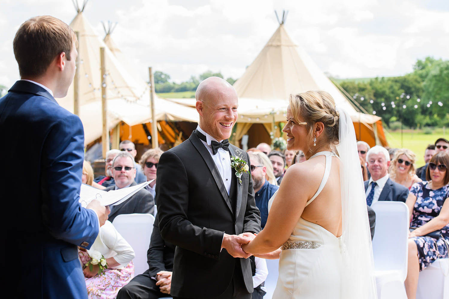 bride and groom holding hands during outside tipi ceremony in Nottingham
