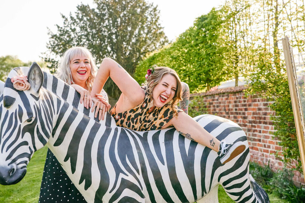 Wedding guest climbing onto a large prop zebra during an outdoor summer wedding.